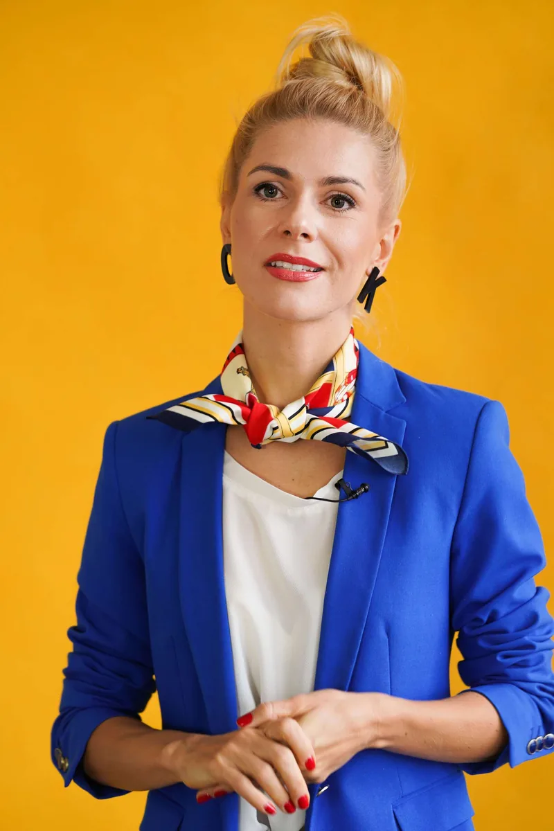 Olga Kairienė geltoname fone, mėlynu švarku ir skarele